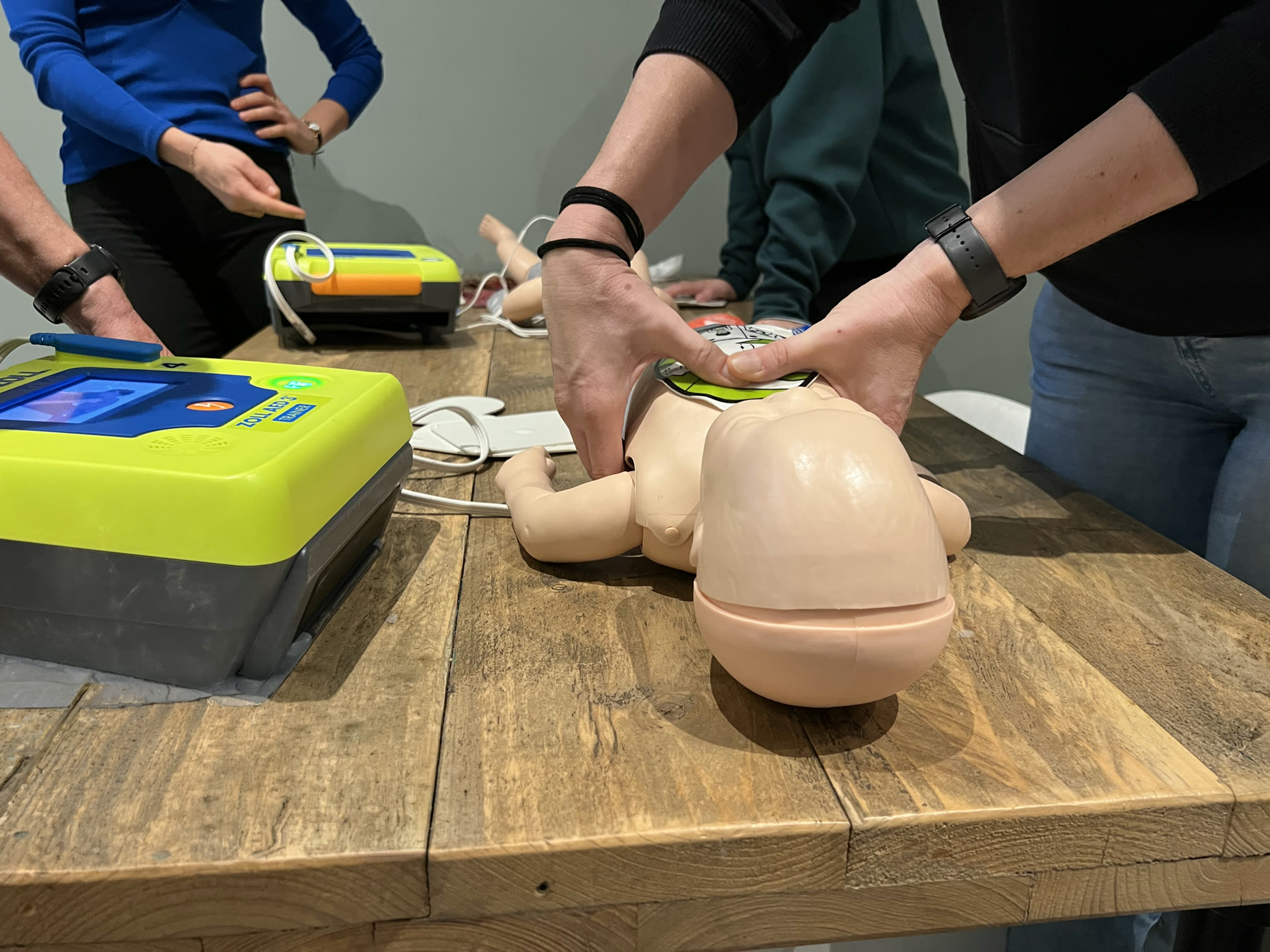 Deelnemers oefenen reanimatie op een pop met een AED tijdens EHBO-bijscholing