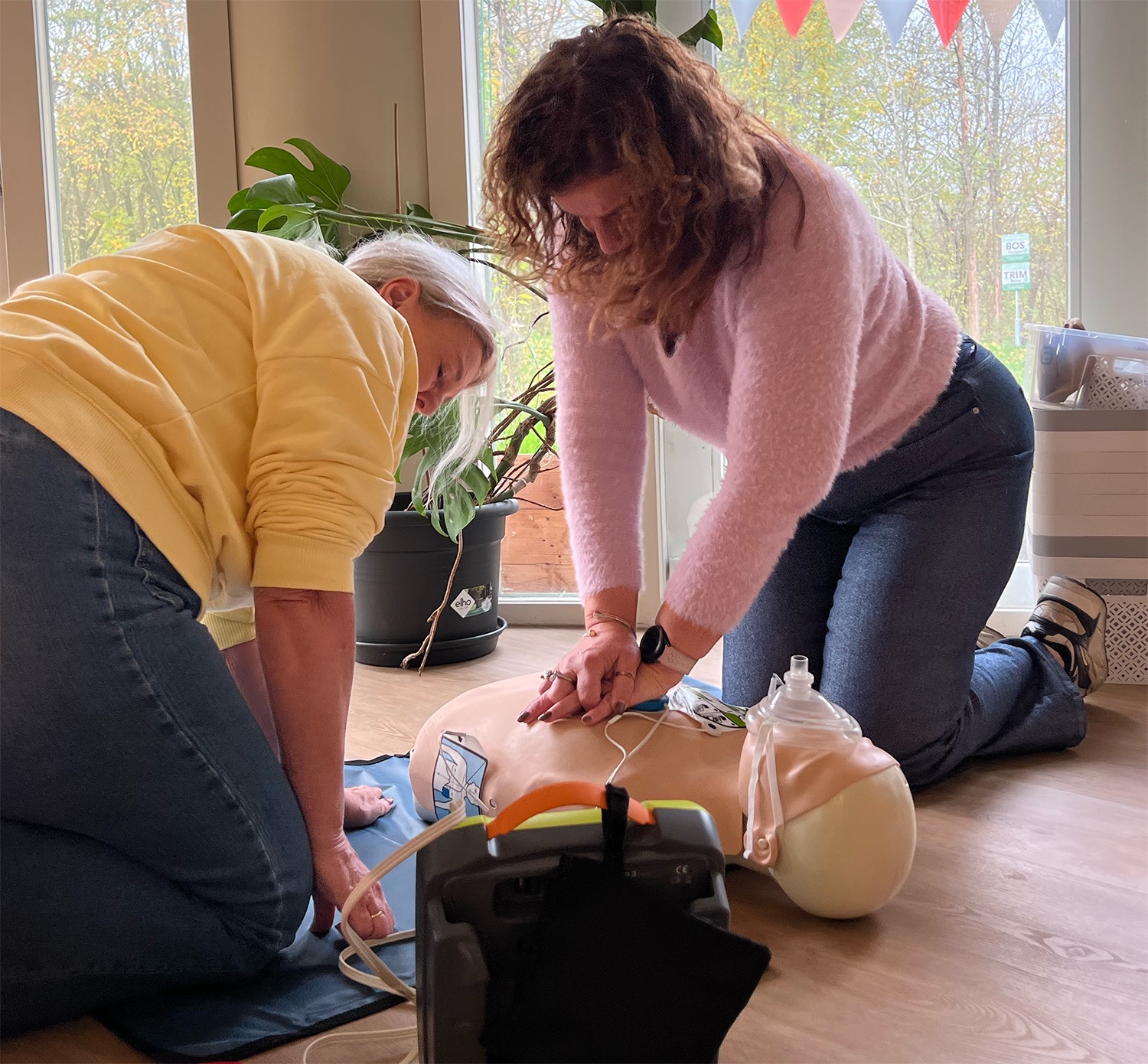 Deelnemers oefenen samen reanimatie en AED-gebruik op een reanimatiepop