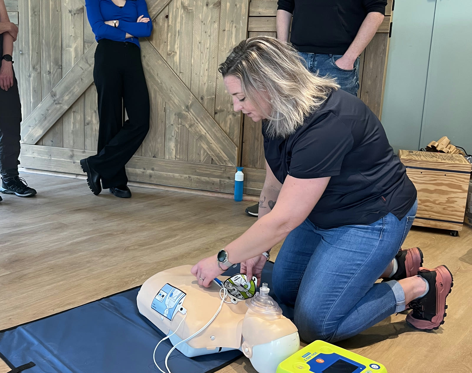 Instructrice oefent reanimatie met een pop op de grond
